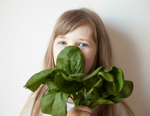 Happy little girl holding a bunch of spinach