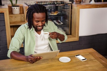 Poster - Man drinking coffee and using tablet