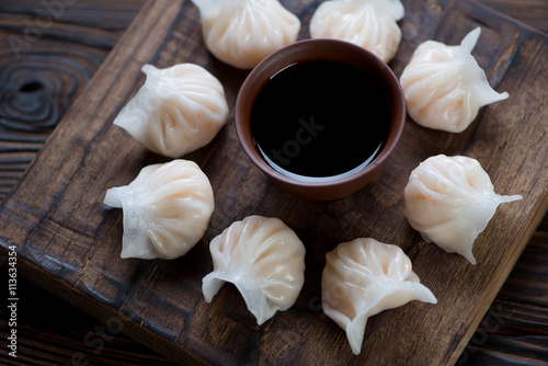 Fényképezés Rustic wooden serving board with steamed dim sums, closeup