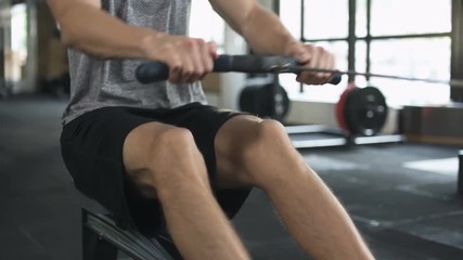 Poster - Handsome concentrated man doing exercise on fitness machine in gym