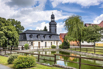 bucha, thuringia, germany: village church with green, pond and trees