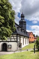 bucha, thuringia, germany: village church with big tree and blue cloudy sky