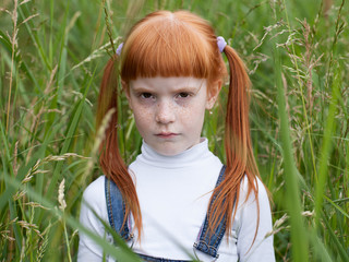 little sad girl with a puffed cheeks looking reproachfully at the camera. portrait close up on a bac