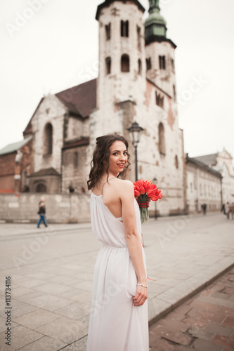 Foto  Beautiful young bride with bridal bouquet on the background church