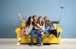 © Africa Studio - Young cheerful friends taking selfie on yellow sofa in the room
