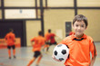 © wckiw - Little boy holding football in futsal gym