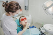 © de Art - female dentist doctor holding dental drill, patient in the dentist's chair