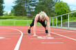 © michaelheim - Single woman stretching calf muscles at race track