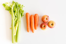 High Angle View Of Celery, Carrots And Apples On A White Table