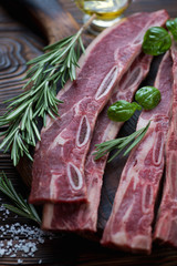 Wall Mural - Closeup of raw beef ribs with rosemary, green basil and sea salt