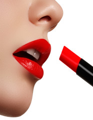 Wall Mural - Close-up shot of woman lips with glossy red lipstick. Extreme close-up on model applying red lipstick. Professional make-up