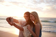 © Jacob Lund - Happy young women taking selfie on the beach