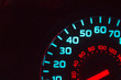 Part of a blue and red speedometer at night