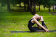 © romankosolapov - Young woman doing gymnastics yoga and stretching in the city park on sunset