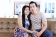 © Creativa Images - Asian couple sitting on the brown couch