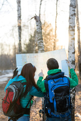 Wall Mural - Young couple hikers looking at map.