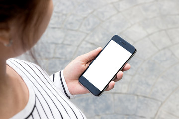 Wall Mural - woman looking phone on road in the city, third-person view