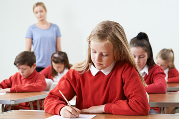 Female Pupil At Desk Taking School Exam