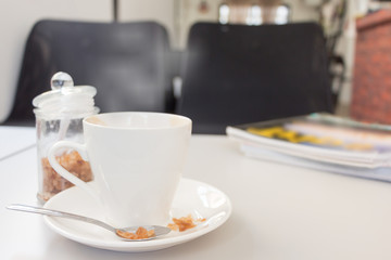 cup of coffee and sugar with magazine on white wood table