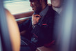 © Fxquadro - African man in a suit using laptop in a car.