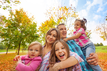 Wall Mural - Happy family play in autumn park hug little kids