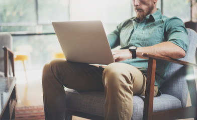 Stylish Businessman working Laptop modern Interior Design Loft Office.Man sitting Vintage chair.Use contemporary Notebook, blurred background.Creative New business Startup Idea.Horizontal,film effect.