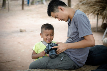 smart photographer  and smiling boy looking photos in camera at