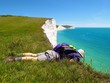 Man looks over white chalk cliff edge at turquoise blue sea