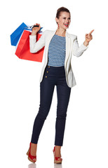 Wall Mural - Smiling young woman with shopping bags pointing on copy space