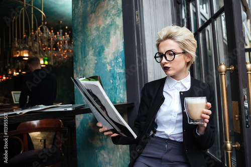 Photographie Close-up portrait d'une jeune fille assise dans le café avec le magazine