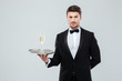 © Drobot Dean - Butler in tuxedo holding tray with glass of champagne