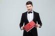 © Drobot Dean - Confident attracive man in tuxedo standing and holding gift box