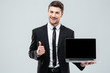 © Drobot Dean - Cheerful businessman holding blank screen laptop and showing thumbs up