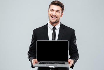 Happy attractive young businessman holding blank screen laptop
