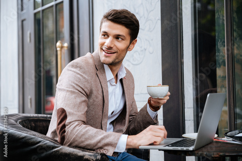 Fotografía Businessman holding cup of coffee and working with laptop outdoors