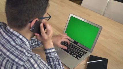 Aufkleber - Young professional worker in the office has call negotiation with client looking on the laptop green screen. Manager has conversation with customer on the smartphone sitting near the wooden desk with