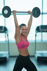 Wall Mural - Fitness Woman Using Barbell Exercising Shoulders Inside Gym