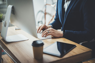 Professional businessman using modern computer while working at office, male lawyer working on technology at vintage loft, retro bike in the background