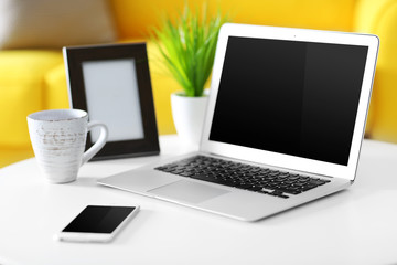Laptop, mobile phone, cup of coffee and empty photo frame indoors
