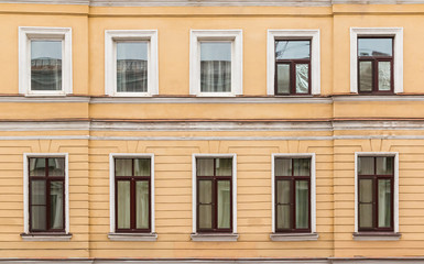 Several windows in a row on facade of urban apartment building front view, St. Petersburg, Russia.