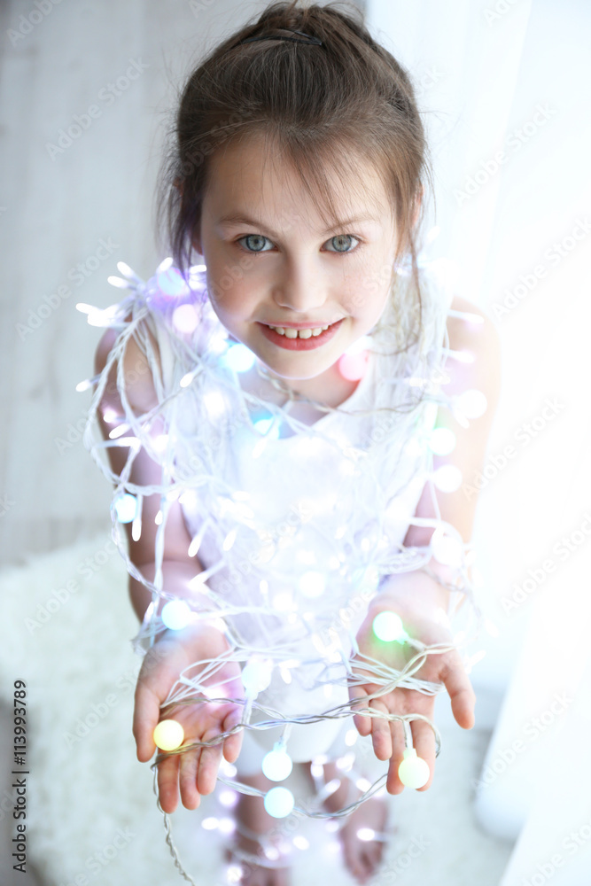 Little girl in light garland at home