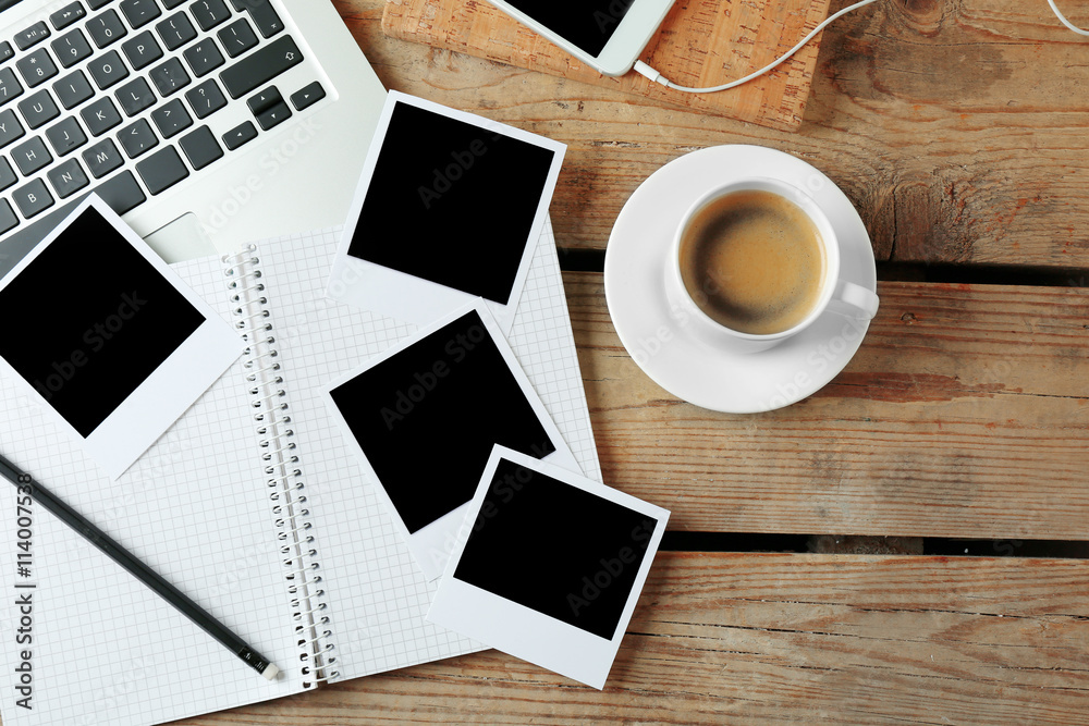 Laptop, notebook and photos on wooden background