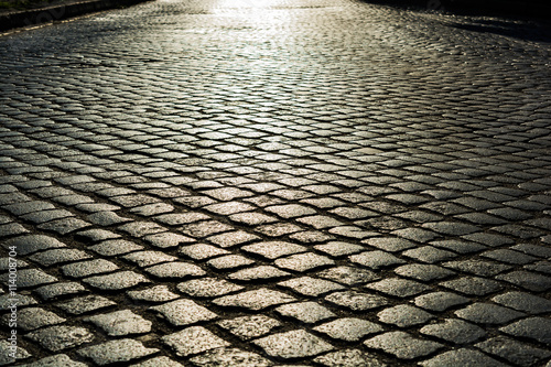 Fotomural sunlight on cobblestone road. old stone texture
