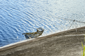 Fish Tank and fishing rod on the shore of the lake on a backgrou