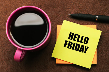 Hello Friday - text on sticky note with a pen and cup of coffee