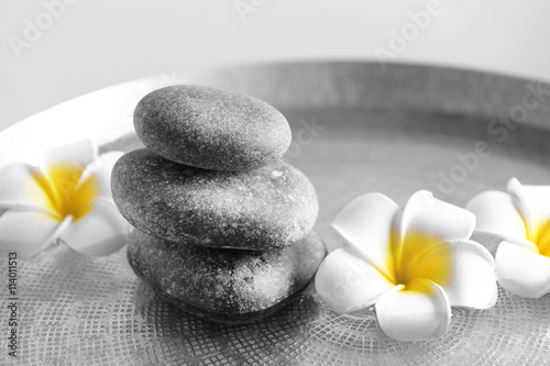 Fototapeta na wymiar Gray spa stones with plumeria flowers, close up