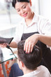 © Svyatoslav Lypynskyy - Picture of hair stylist or barber girl drying man's hair with hair dryer. Handsome man having his hair dried in hairdressing saloon.