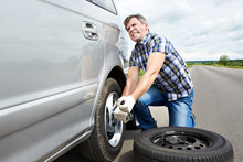 Man Changing A Spare Tire Of Car