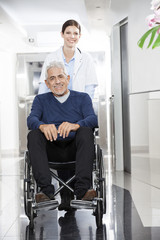 Wall Mural - Female Doctor Pushing Senior Patient In Wheel Chair