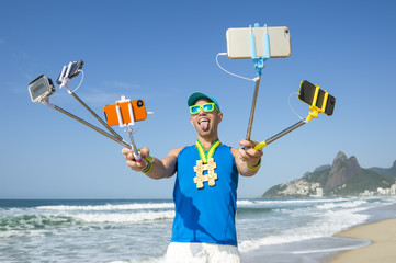 Hashtag gold medal athlete posing for a picture with mobile phones on selfie sticks on Ipanema Beach in Rio de Janeiro, Brazil